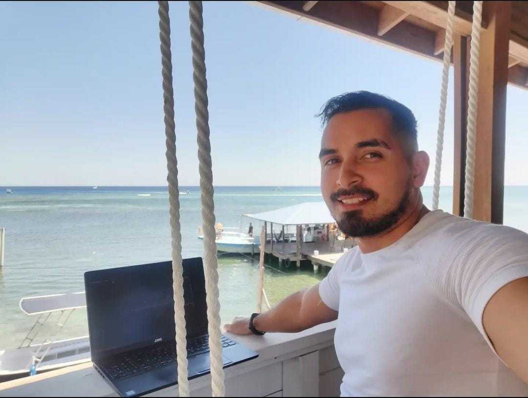 a man smiling on the beach while working